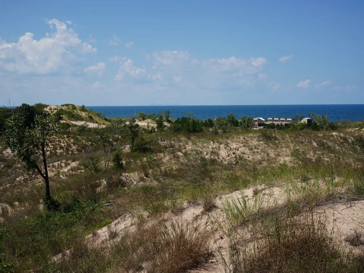 Sandy beach with dunes and a distant city skyline on the horizon
