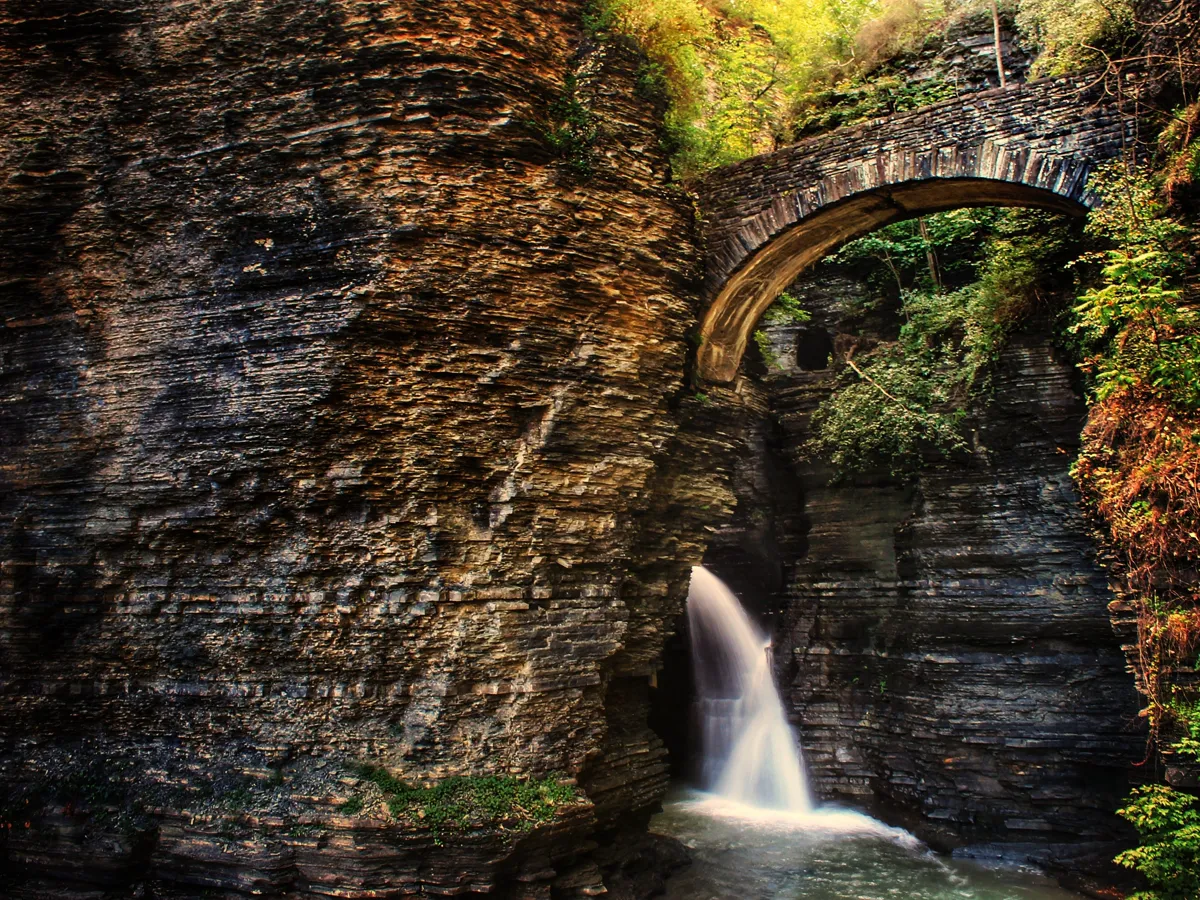 Narrow gorge with a thin waterfall dropping between steep wooded walls