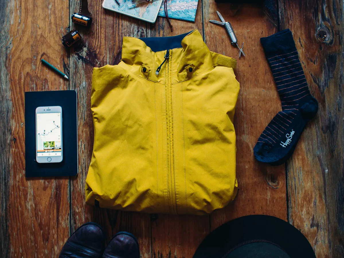 Folded jacket, hat and gloves on a pack at a trailhead in early morning light