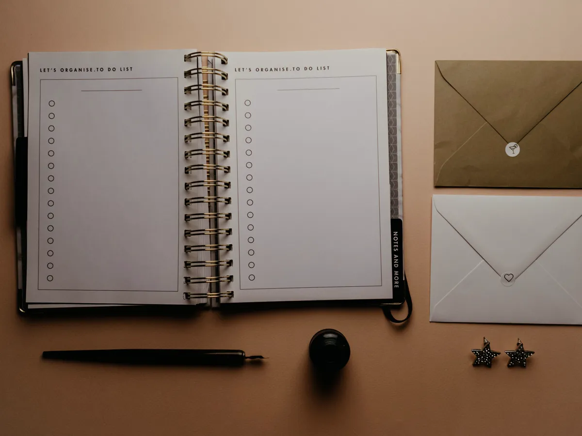 Printed itinerary and packing checklist on a wooden table beside a folded trail map
